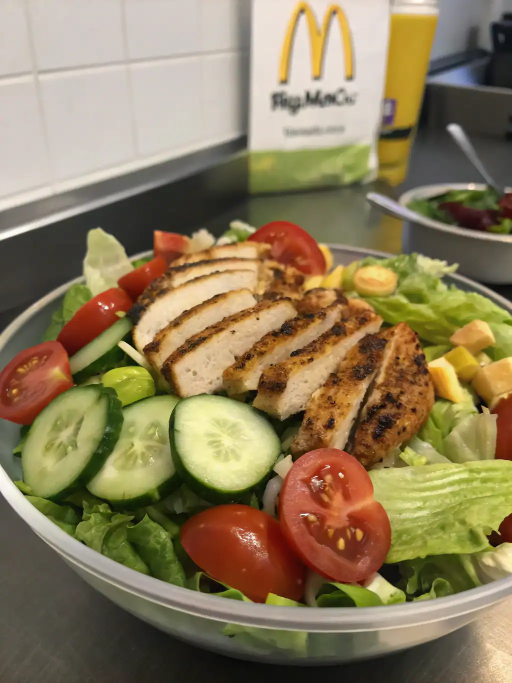 Fresh grilled chicken salad with cucumbers, cherry tomatoes, lettuce, and shredded cheese served in a white bowl for a healthy meal.