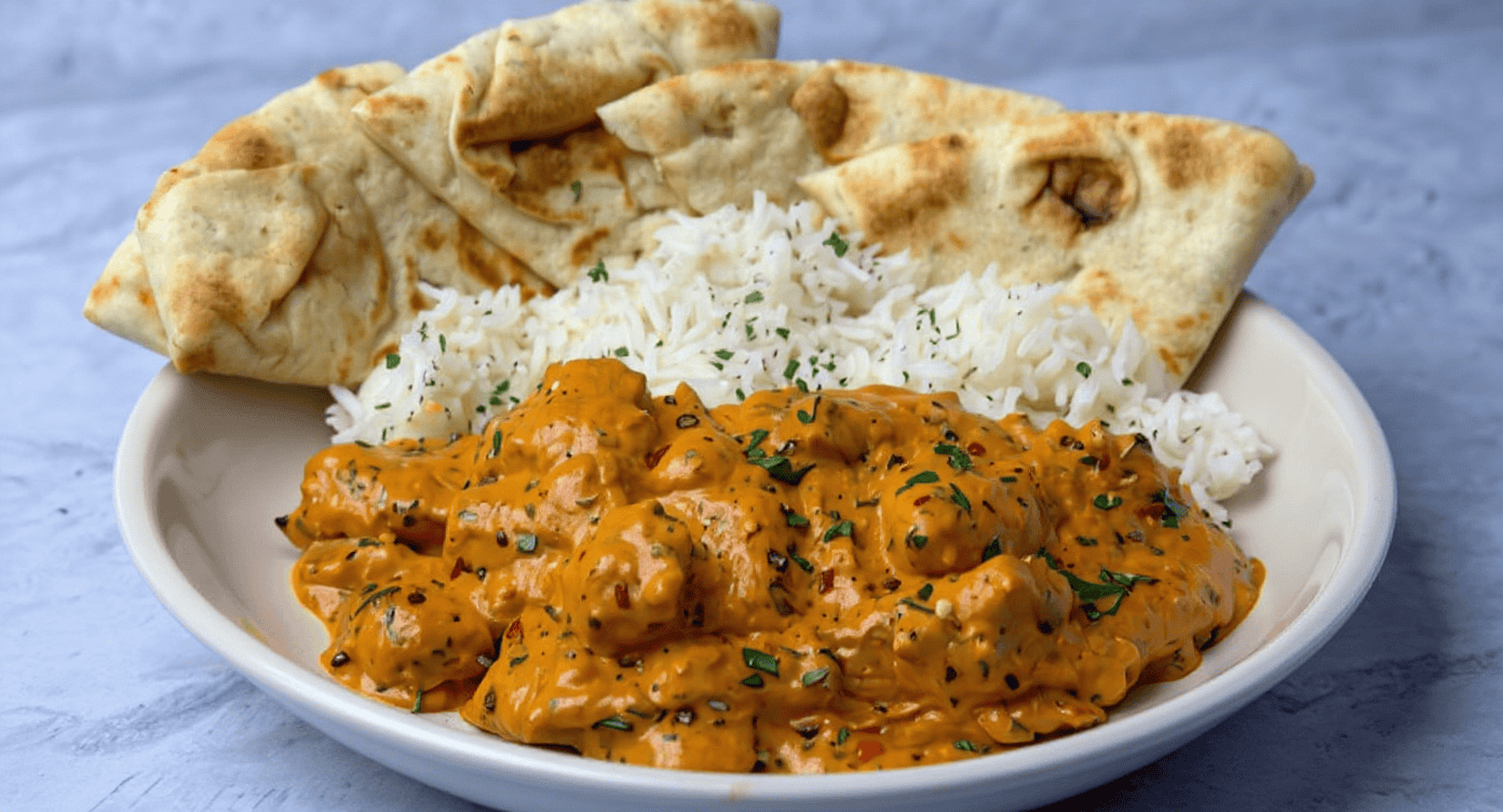 Spicy shrimp curry with rice and chapati on a white plate, showcasing flavorful Indian cuisine.
