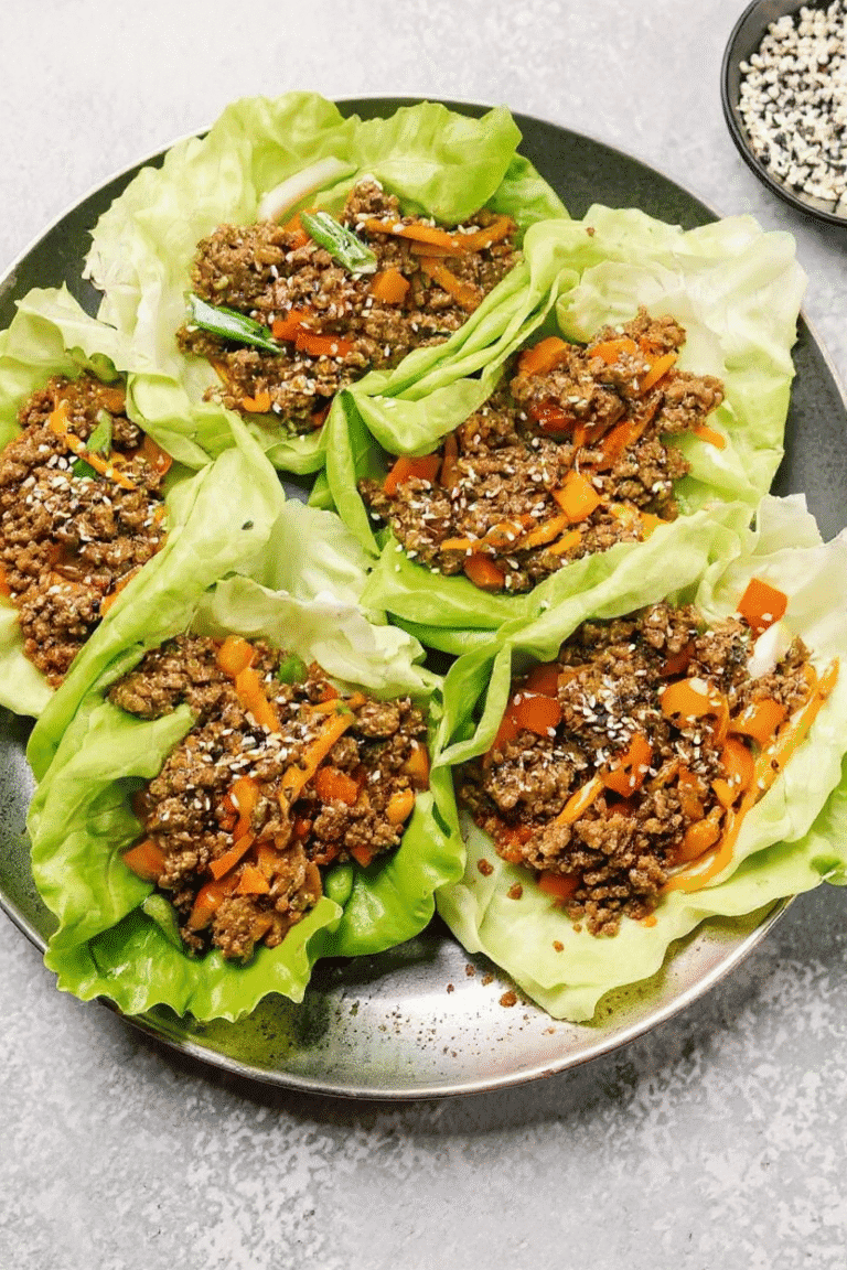 Ground beef lettuce wraps with diced vegetables and sesame seeds, served on a black plate, optimized for healthy meal recipes and easy, delicious Asian-inspired lunch ideas.